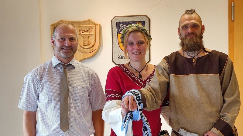 Standesbeamter Hans Geiger mit dem frisch vermählten Brautpaar Ramona und Daniel Jetz. Für das Hand-Fasting, ein Hochzeitsritual der Wikinger, verwendete er einen Schal des TSV 1860 München.