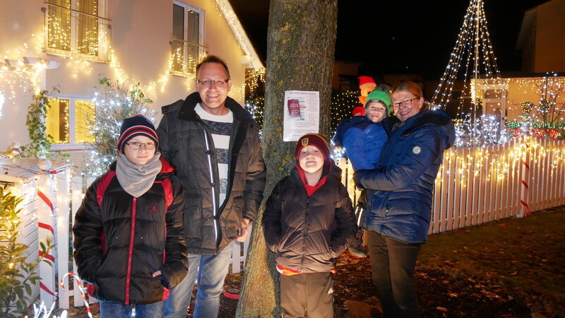 Familie Hesse vor ihrem aufwendig geschmückten Haus in Furth. Ein Plakat am Baum informiert über die Spendenaktion.