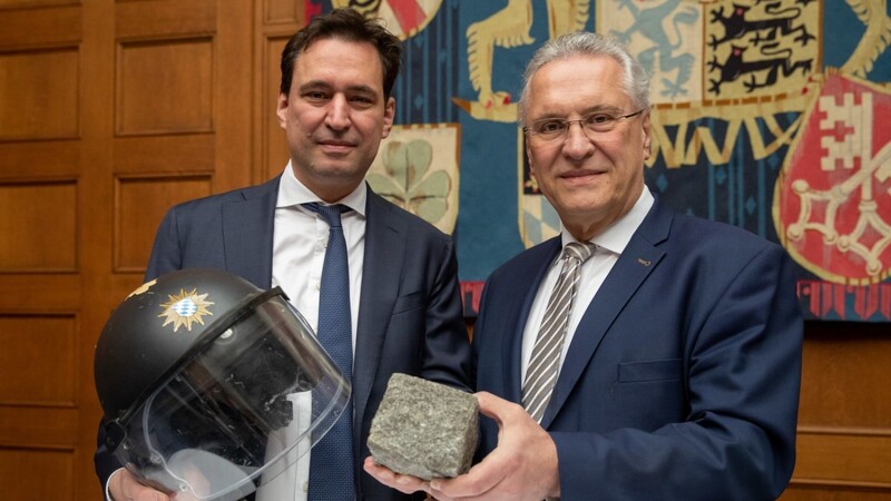 Justizminister Georg Eisenreich (l.) und Innenminister Joachim Herrmann haben den Aktionsplan "Gewalt gegen Einsatzkräfte" präsentiert und zeigten einen Helm, der durch einen Stein beschädigt wurde.