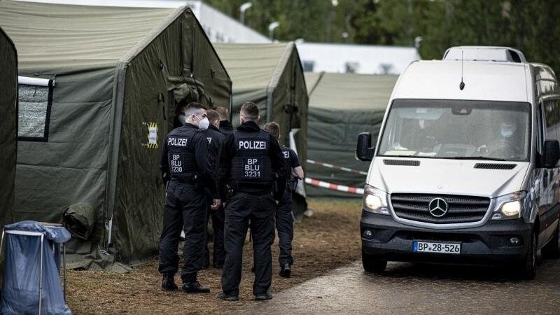 Polizisten in der Erstaufnahmeeinrichtung Eisenhüttenstadt neben einem Zelt für neu ankommende Asylsuchende.