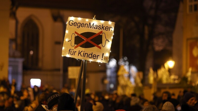 Teilnehmer einer Demonstration gegen die Corona-Maßnahmen halten ein Plakat mit der Aufschrift "Gegen Masken für Kinder".