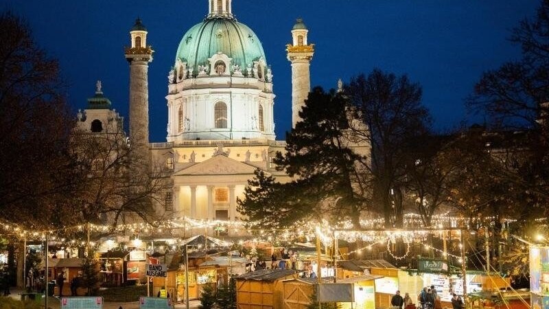 Menschen besuchen den Christkindlmarkt am Karlsplatz in Wien.