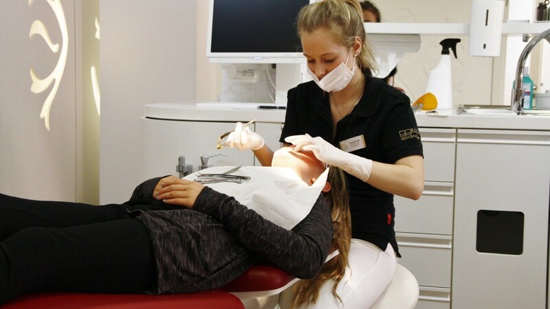 Vorsichtig setzt Verena Decker ihrer Patientin den Draht für die Zahnspange ein.