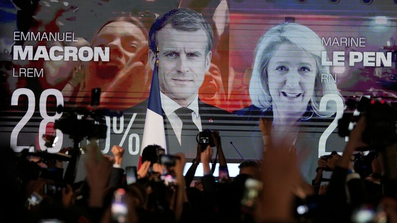 Ein Bildschirm in Paris zeigt den französischen Präsidenten Macron und die rechtsextreme Kandidatin Le Pen am Wahltag. Die beiden kämpfen in einer Stichwahl am 24. April um das höchste Amt im Land.