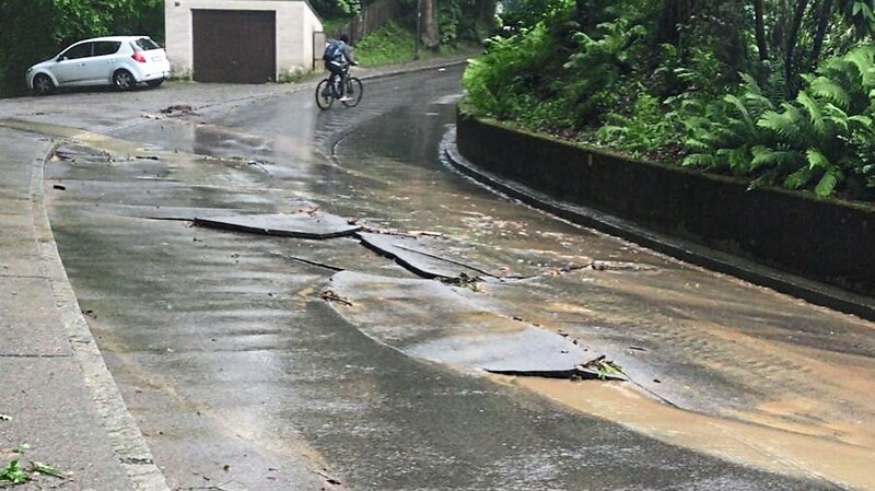 Der Regen schwemmt eine Straße so stark auf, dass der Asphalt bricht.