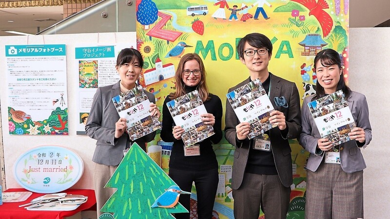 Zusammen mit drei Mitarbeitern im Bürgerbüro präsentiert Stefanie Reetz das neue Stadtmagazin von Moriya, das sich mit dem 30-jährigen Jubiläum der Städtepartnerschaft mit Mainburg beschäftigt.