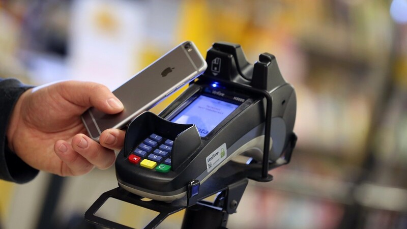 Ein Smartphone wird an den Bezahl-Terminal an der Kasse eines Supermarktes gehalten. Das kontaktlose Bezahlen wird in Deutschland populärer.