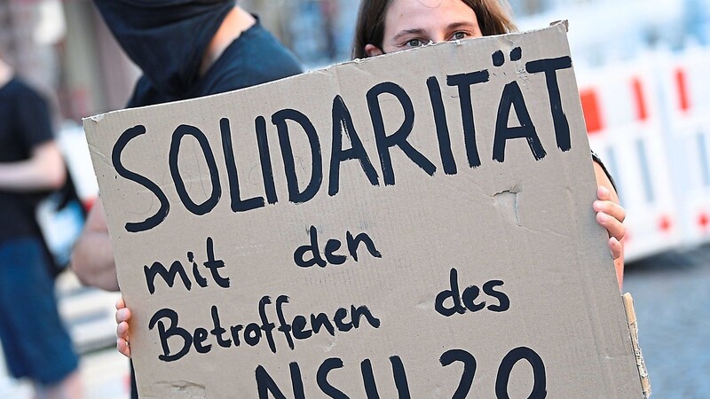 Eine Demonstrantin hält während einer Kundgebung in der Wiesbadener Innenstadt ein Plakat. In der Affäre um rechtsextreme Drohschreiben wird jetzt auch gegen einen Ex-Polizisten aus Niederbayern ermittelt.