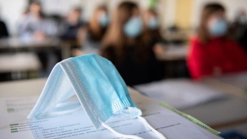 Ein Mund-Nasen-Schutz liegt im Unterricht auf Unterlagen.