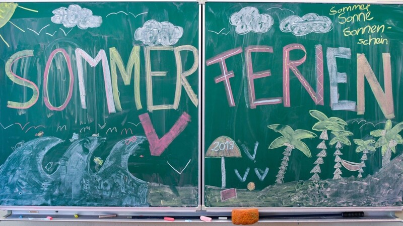 "Sommerferien" steht in großen, bunten Buchstaben an der Tafel einer Grundschule. Der erste Ferientag in Bayern wäre heuer Montag, der 27. Juli - wenn es nicht noch anders kommt.