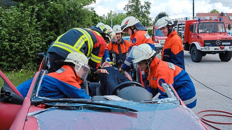 Nach dem Abtrennen des Daches mit der schweren hydraulischen Rettungsschere sind alle Hände notwendig, um die Übungspuppe patientengerecht aus dem Fahrzeug zu retten.