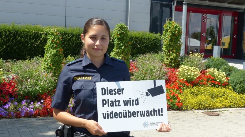 Polizeimeisterin Simone Kölbl mit einem der Hinweisschilder "Dieser Bereich wird videoüberwacht".