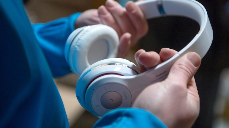 Ein Junge hält Kopfhörer in der Hand. Podcasts eignen sich gut zum Zeitvertreib während der Ausgangsbeschränkungen.