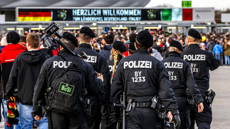 Einsatzkräfte der Polizei beobachten am 29.03.2016 in München (Bayern) den Stadioneingang der Allianz Arena vor dem Länderspiel Deutschland - Italien. Bayern soll mehr Polizisten mit ausländischen Wurzeln bekommen.