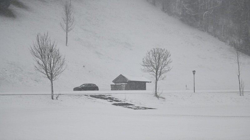 Ein Auto fährt durch die winterlich verschneite Landschaft.