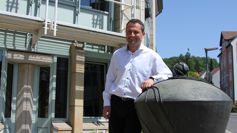Markus Brunhofer vor seinem Büro in Amberg. Das Pendel, an dem er lässig lehnt, ist Symbol eines frühen Messinstrumentes. Pendel wurden in der Geodäsie eingesetzt.