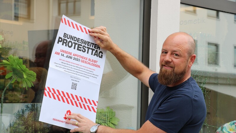 Benjamin Striegan, Sprecher der Apotheker im Landkreis Regen, bringt das Plakat zum bundesweiten Protesttag an.
