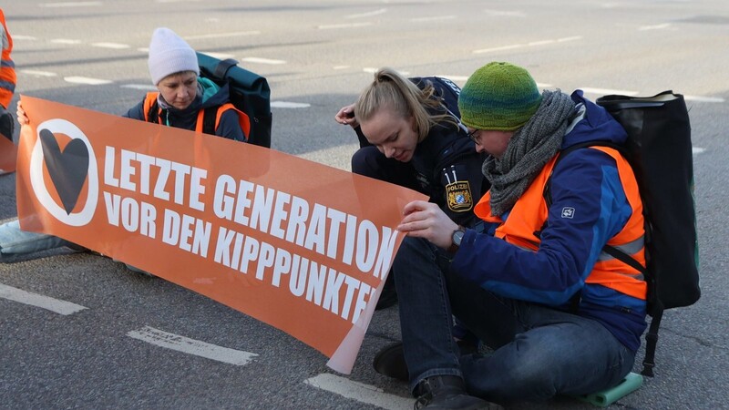 Klimaaktivisten blockieren die Galgenbergkreuzung vor den Arcaden in Regensburg.