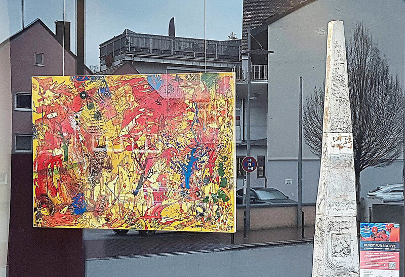 Das Bild "Life is beautiful" von Heidrun Hee in Acryl-Mischtechnik und eine der Stelen von Katalin Bereczki-Kossack im Fenster der Mainburger Abens-Apotheke. 