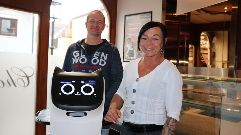 Melanie und Thomas Bittner in ihrem Café "Chocolate" - zusammen mit ihrer "Mitarbeiterin" Bella: einem Servierroboter.
