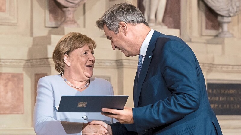 Im prunkvollen Antiquarium der Münchner Residenz erhält Altkanzlerin Angela Merkel aus den Händen von Ministerpräsident Markus Söder eine der höchsten Auszeichnungen des Freistaats.