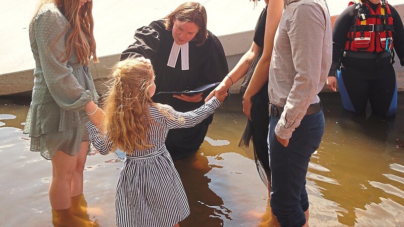 Im Wasser stehend spendet Pfarrerin Lisa Hacker das Taufsakrament.