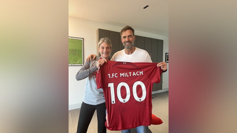 Mona Nemmer und Trainer Jürgen Klopp präsentieren das signierte Liverpool-Trikot, das künftig im Vereinsheim hängen wird.