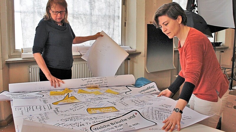 Birgitta Petschek-Sommer (l.) und Anja Braehmer über eine Tischdecke mit Impulsfragen und -antworten aus einem kürzlichen Stadtgespräch gebeugt. In die Planung der neuen Dauerausstellung wollen sie besonders viele Bürger, ihre Erinnerungen und Ideen miteinbeziehen.