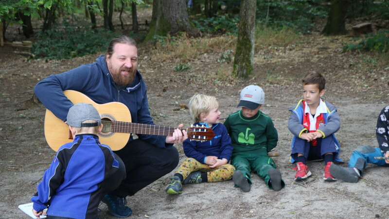Patrick Sieber mit seiner Gitarre zusammen mit den Waldkindergartenkindern im Morgenkreis.