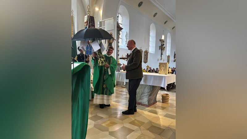 Kirchenpfleger Josef Baun überreicht den mit Grüßen geschmückten Schirm