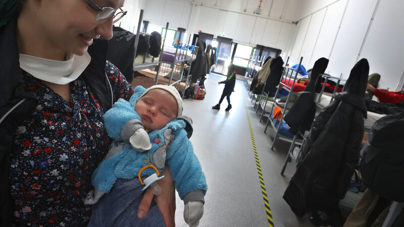 Eine geflüchtete Ukrainerin hält in einem Augsburger Schlafsaal ihr Baby auf dem Arm.
