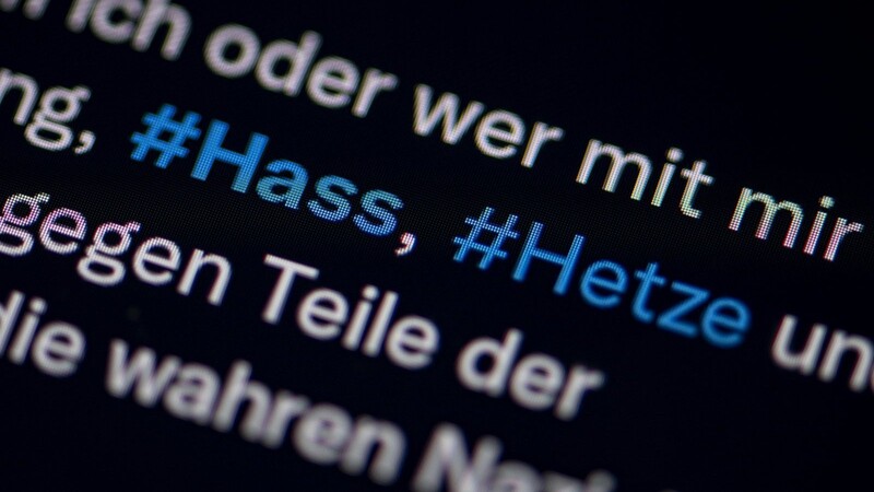 Auf dem Bildschirm eines Smartphones sieht man die Hashtags Hass und Hetze in einem Twitter-Post. Auch wenn 2022 die Zahl der angezeigten Straftaten im Netz in Bayern auf 1.186 leicht zurück ging, verbleibt sie weiterhin auf einem hohen Niveau.