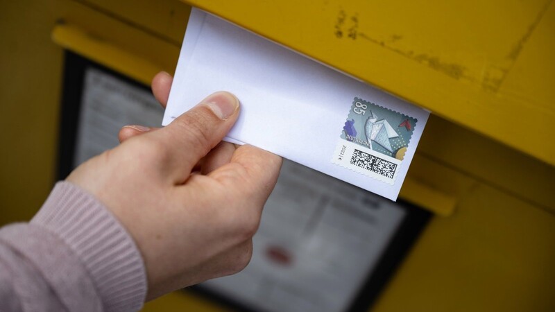 Eine Frau wirft einen Standardbrief in einen Briefkasten. Die Deutsche Post darf das Briefporto nicht vorzeitig erhöhen. Ein entsprechender Antrag sei abgelehnt worden, teilte die Bundesnetzagentur mit.
