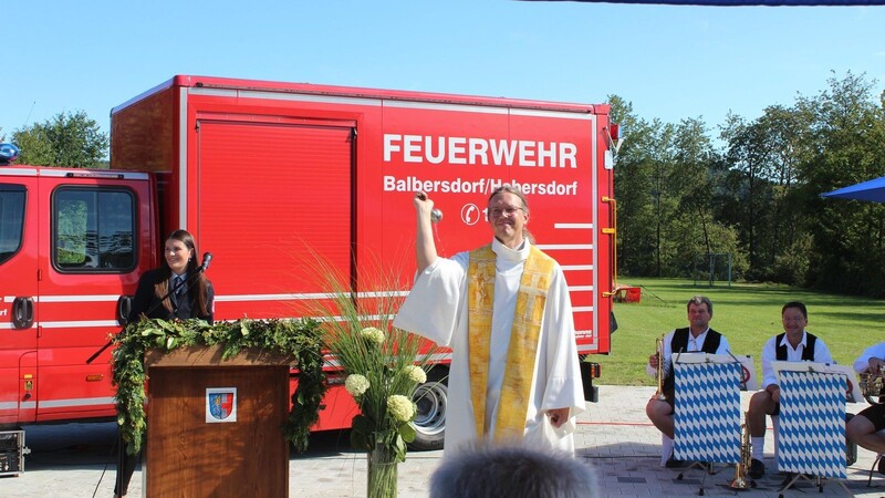 Pfarrer Michael Reißer segnet das neue Feuerwehrauto und die Gäste.