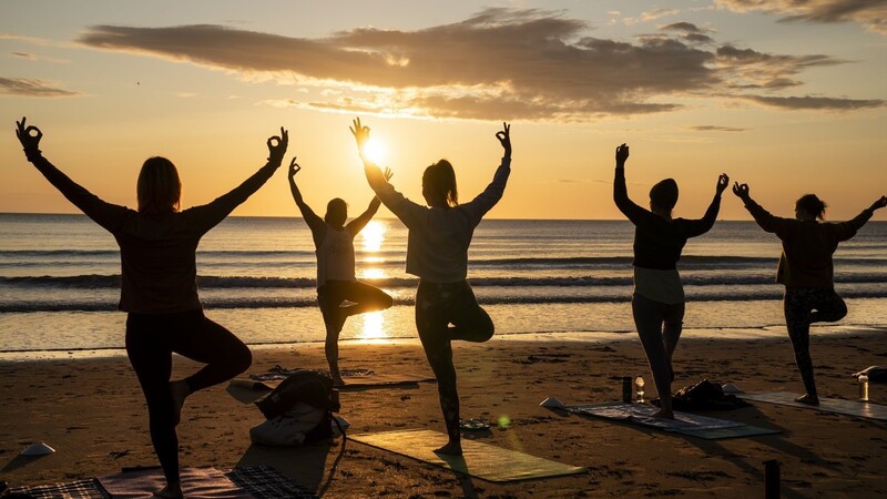 Yoga-Übungen am Strand, gut für Körper und Geist: Viele Deutsche lassen trotz besseren Wissens ihre Gesundheit sitzen.