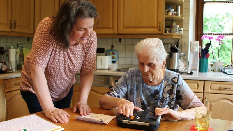 Ruth Nolte (links) erklärt Krista Hehberger, wie sie mit einem Gerät Hörbücher abspielen kann.