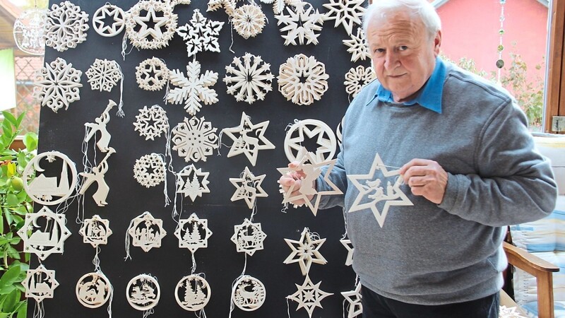 Michael Gruber vor seiner "Ausstellungswand", die eine kleine Auswahl der unzähligen Formen und Varianten seiner Sterne zeigt.