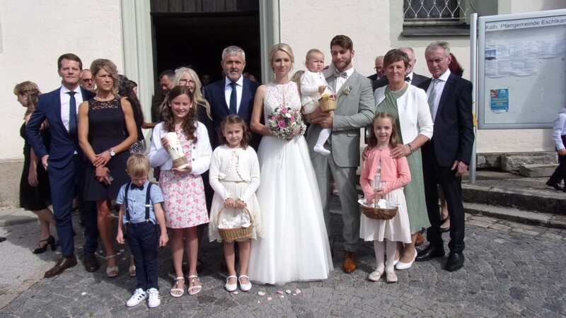 Das Brautpaar mit Eltern und Angehörigen beim Verlassen der Pfarrkirche, die Blumenmädchen streuten Rosenblüten für das Brautpaar aus.
