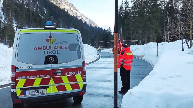 Ein Krankenwagen und zwei Hubschrauber blockieren im Ortsteil Ammerwald die Straße. Bei einem Lawinenabgang unweit der deutsch-österreichischen Grenze sind nach Polizeiangaben zwei Skitourengänger aus dem Landkreis Cham verschüttet worden.