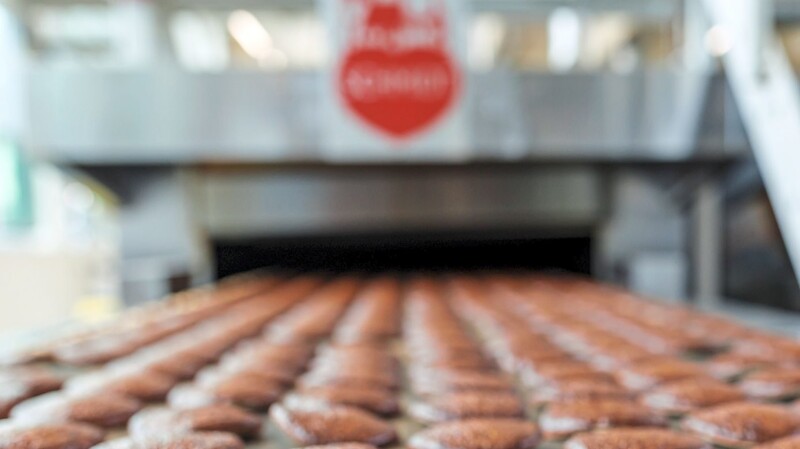 Frisch gebackene Lebkuchen laufen auf einem Band aus einem Ofen in der Produktion des Lebkuchenherstellers Schmidt in Nürnberg.
