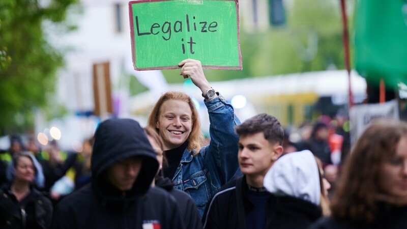 "Legalize it" steht auf einem Plakat, das ein Demonstrant während einer Demonstration zur Cannabislegalisierung hält. Die teilweise Durchsetzung der Legalisierung in Deutschland sorgt EU-weit für Diskussionen.