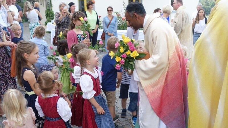 Mit Blumen begrüßen Kinder des Dreifaltigkeits-Kindergartens den neuen Geistlichen an der Kirchentür.