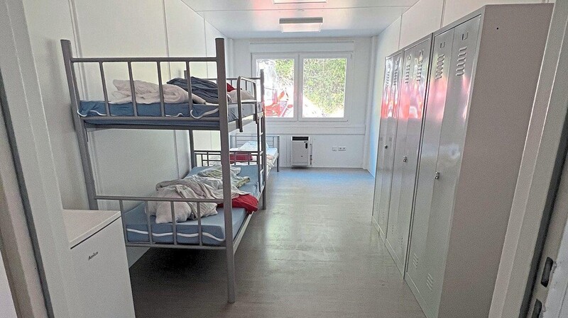 Ein Dreibettzimmer im Container: Vorne das Doppelstockbett, hinten steht ein einzelnes Bett.