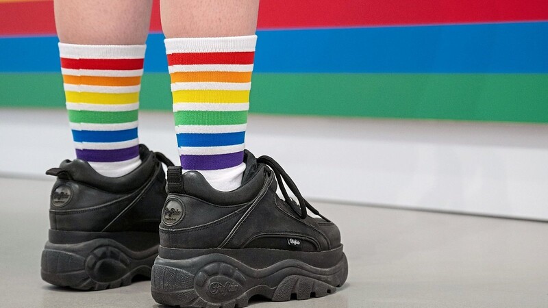 Eine Person trägt Socken in den Regenbogenfarben - Zeichen dafür, dass sie der queeren Community aufgeschlossen gegenübersteht und keinerlei Probleme mit sexueller Vielfalt hat.
