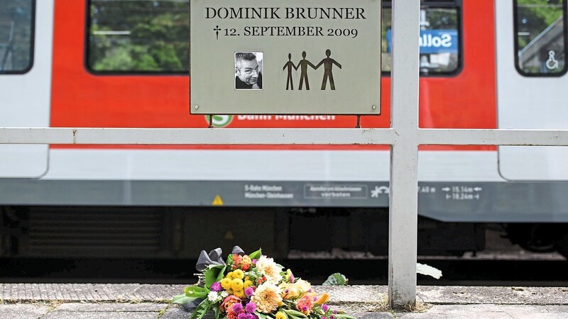 Frische Blumen mit einer Trauerschleife liegen am zehnten Jahrestag des Verbrechens unter der Gedenktafel in Solln.