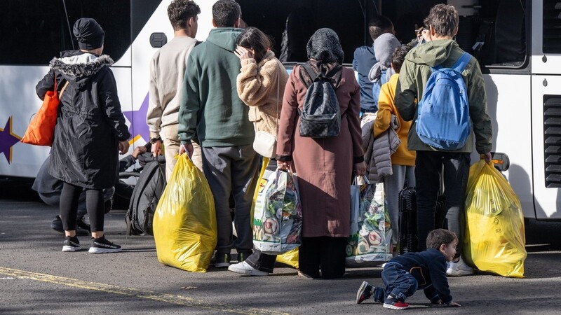 Flüchtlinge gehen in der hessischen Erstaufnahmeeinrichtung (HEAE) in Gießen zu einem wartenden Bus.
