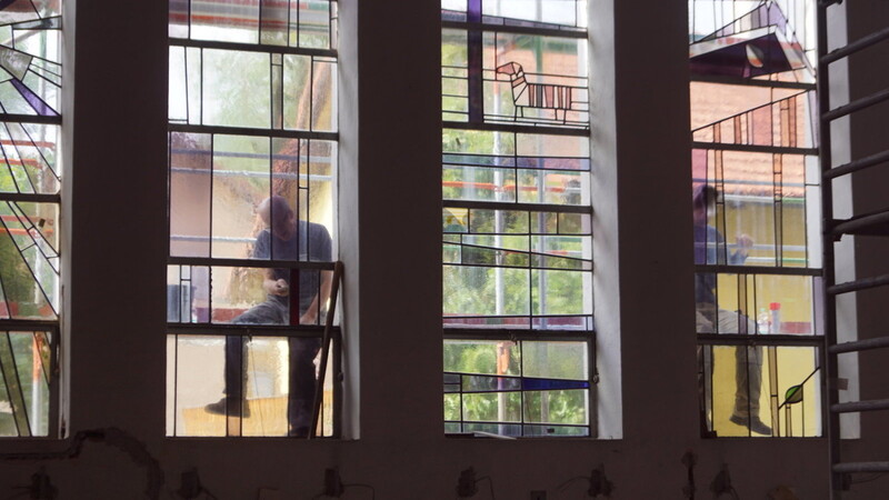 Glasmonteur Peter Adrian (links) und sein Kollege Lukas Diermann arbeiten an der großen Fensterfront der Christuskirche. Im Fenster zwischen den beiden ist oben das Lamm Gottes zu sehen.