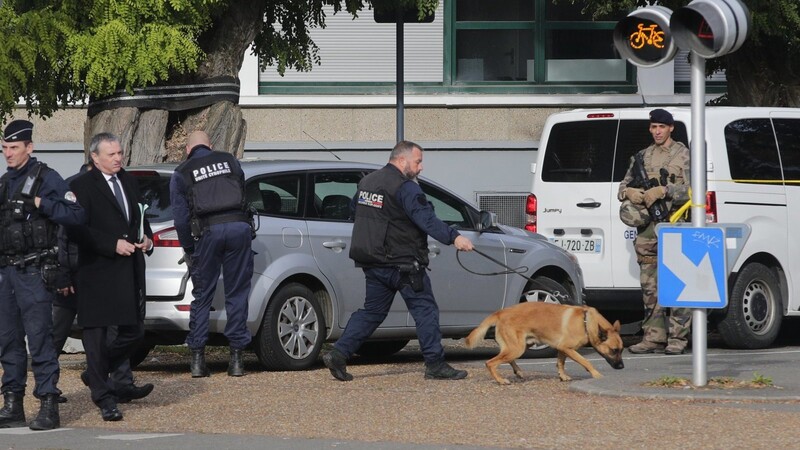 Polizeibeamte mit einem Spürhund treffen während eines Bombenalarms an einer Schule in Arras ein.
