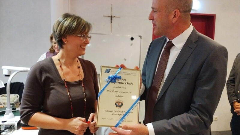 Schulleiter StD Clemens Kink überreicht der ungarischen Lehrerin die Urkunde zur 25-jährigen Schulfreundschaft.