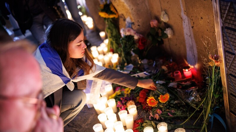 Eine junge Frau legt bei einer Gedenkveranstaltung vor der Münchner Hauptsynagoge Blumen nieder.